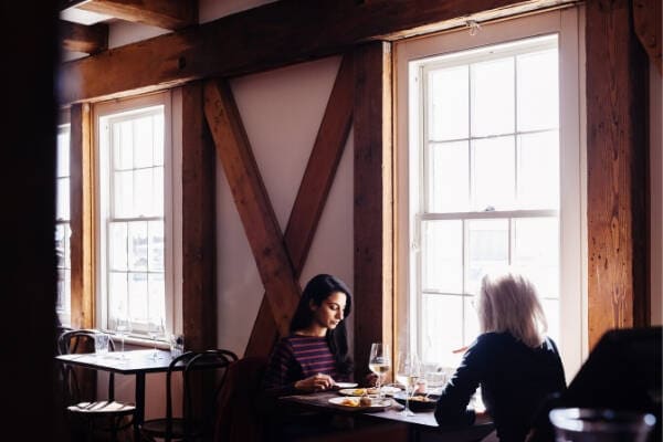 A cozy dining scene with two women enjoying their meals at Stillwater Restaurant in Launceston, Tasmania, featuring diners enjoying their meals at elegantly set tables.